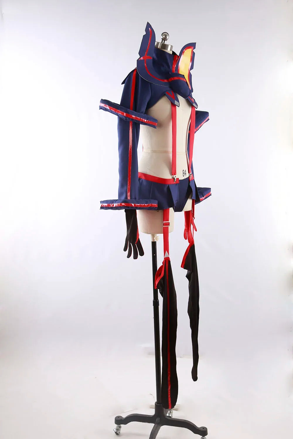 Cosplay costume on mannequin, side view: navy jacket with red accents and black strapped leg covers