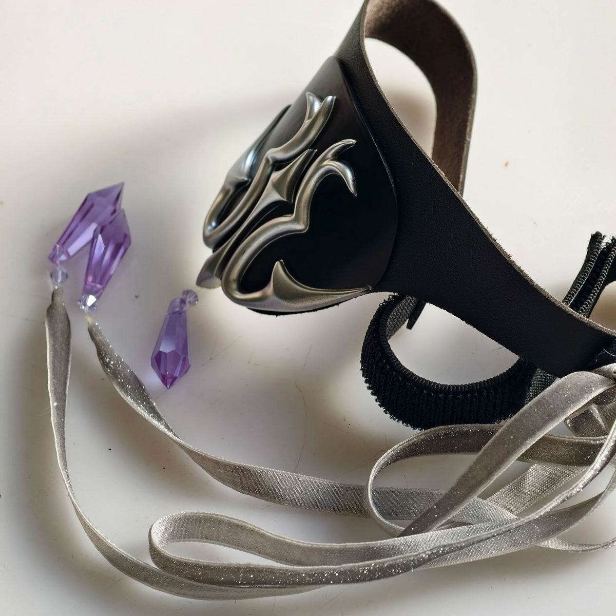 Black eye mask with silver flame emblem, black elastic and silver satin ribbon ties