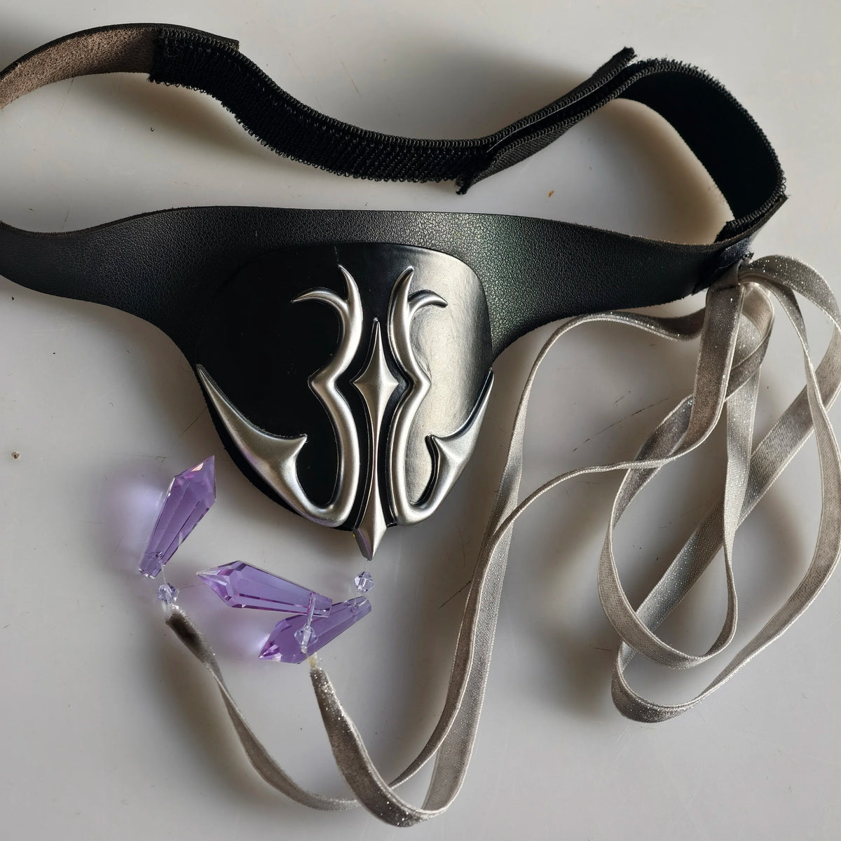 Black eye mask with silver flame emblem and black elastic, silver satin ribbon ties