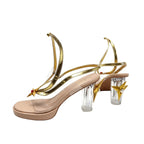 Nude pink platform high-heel sandals with gold trim, clear stacked heels, red jewel ornaments